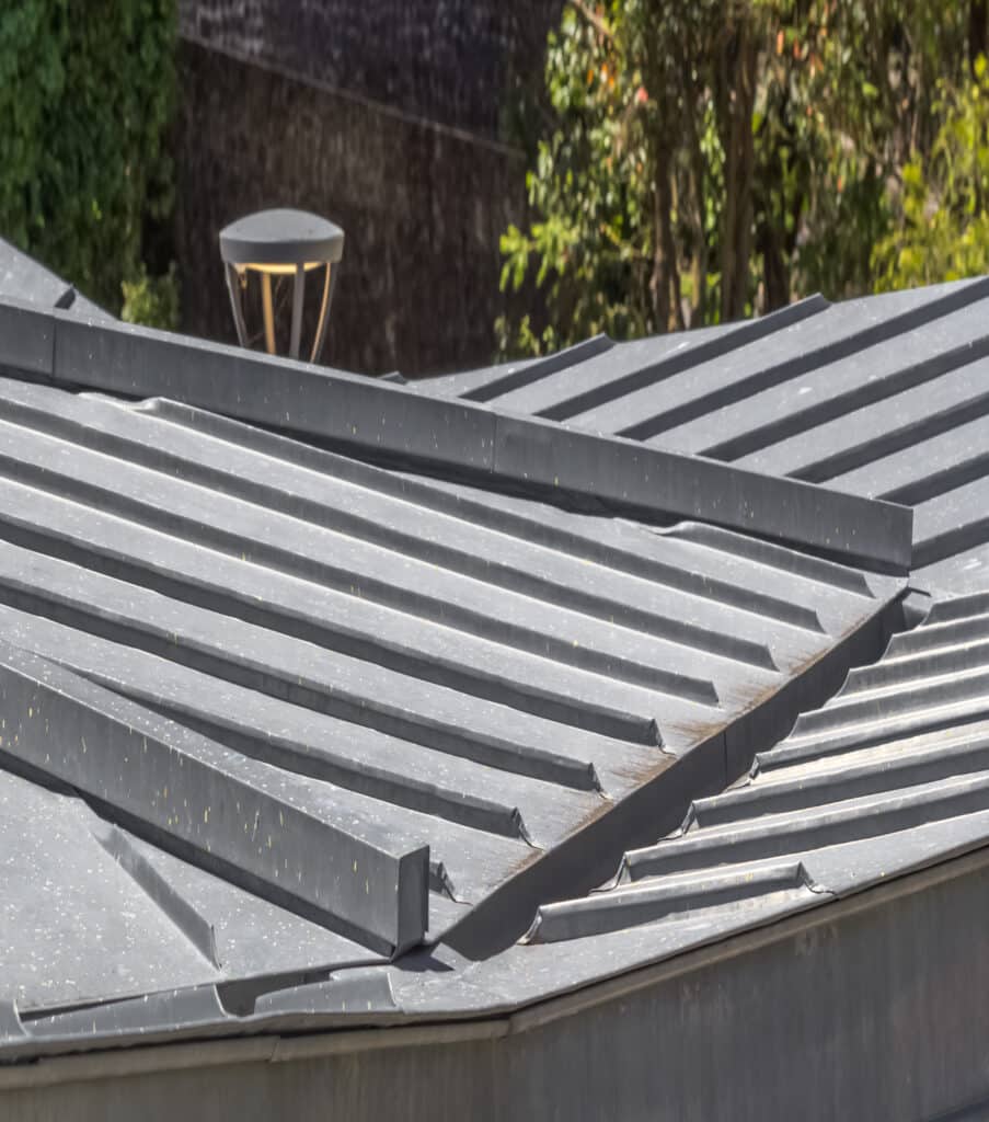Toiture Métallique Grise à Joint Debout pour Maison Moderne Toiture métallique grise à joint debout avec différentes pentes sous un éclairage extérieur naturel.